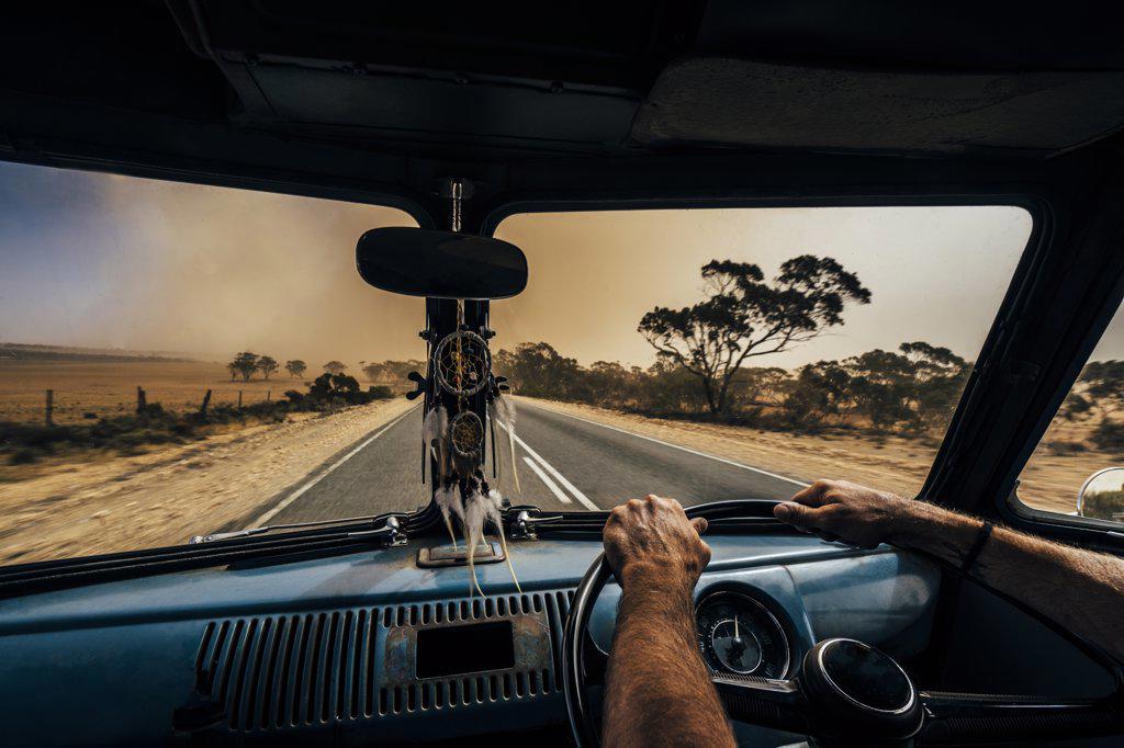 Man driving van on remote desert road, Australian bush
