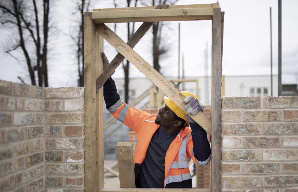 Male construction worker installing door frame at construction site
