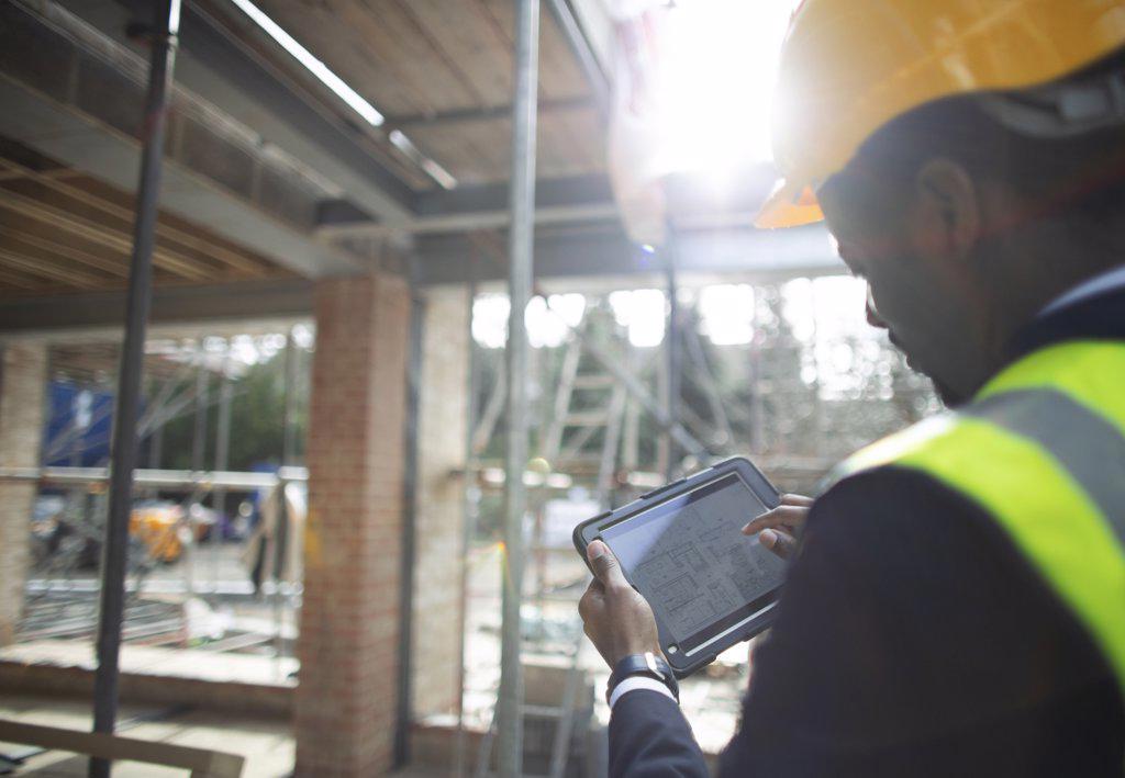 Male architect looking at digital blueprints at construction site