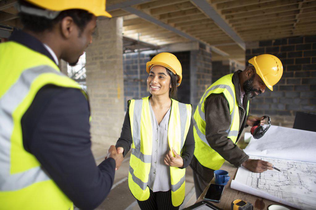 Architect and forewoman shaking hands at construction site