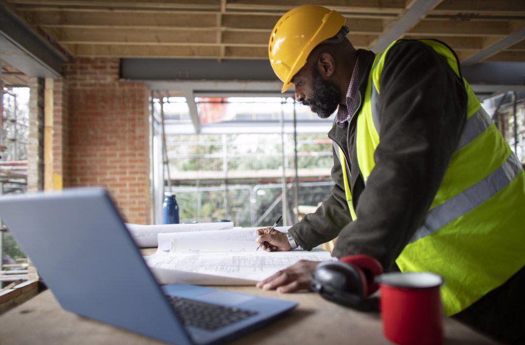 Male architect reviewing blueprints at construction site