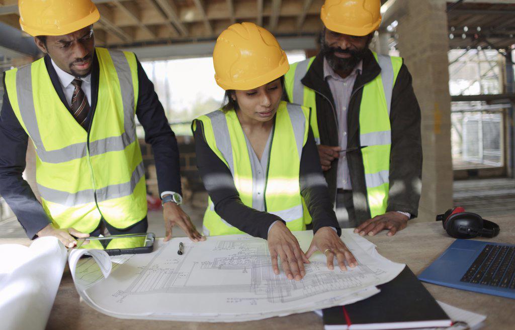 Architects discussing blueprints at construction site