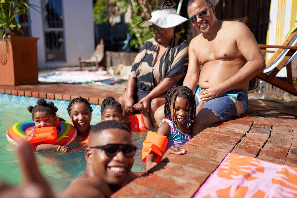 Portrait happy multigenerational family at sunny summer swimming pool