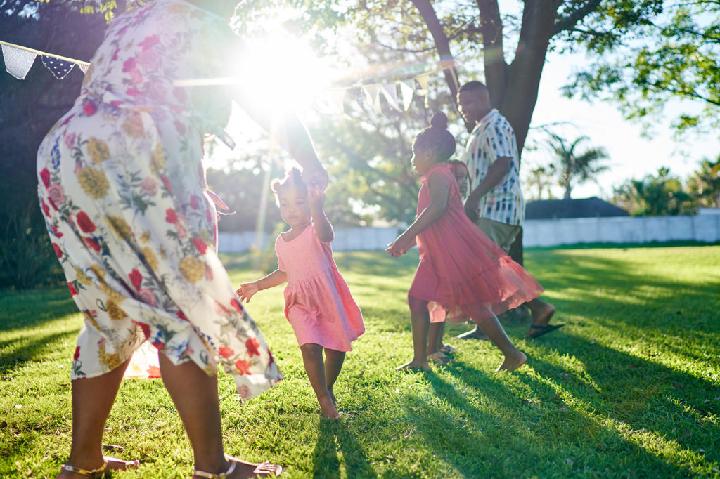 Family dancing in sunny summer backyard