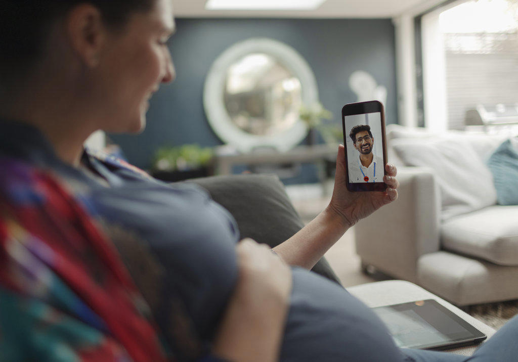 Pregnant woman video chatting with doctor on smart phone screen