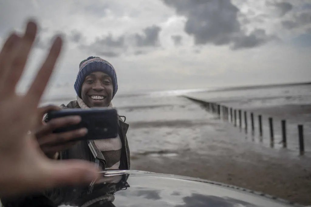 Happy man with camera phone on winter beach