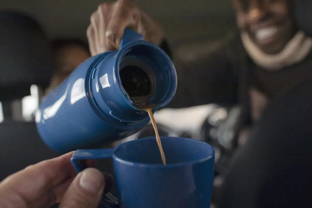 POV close up man pouring coffee from thermos into cup