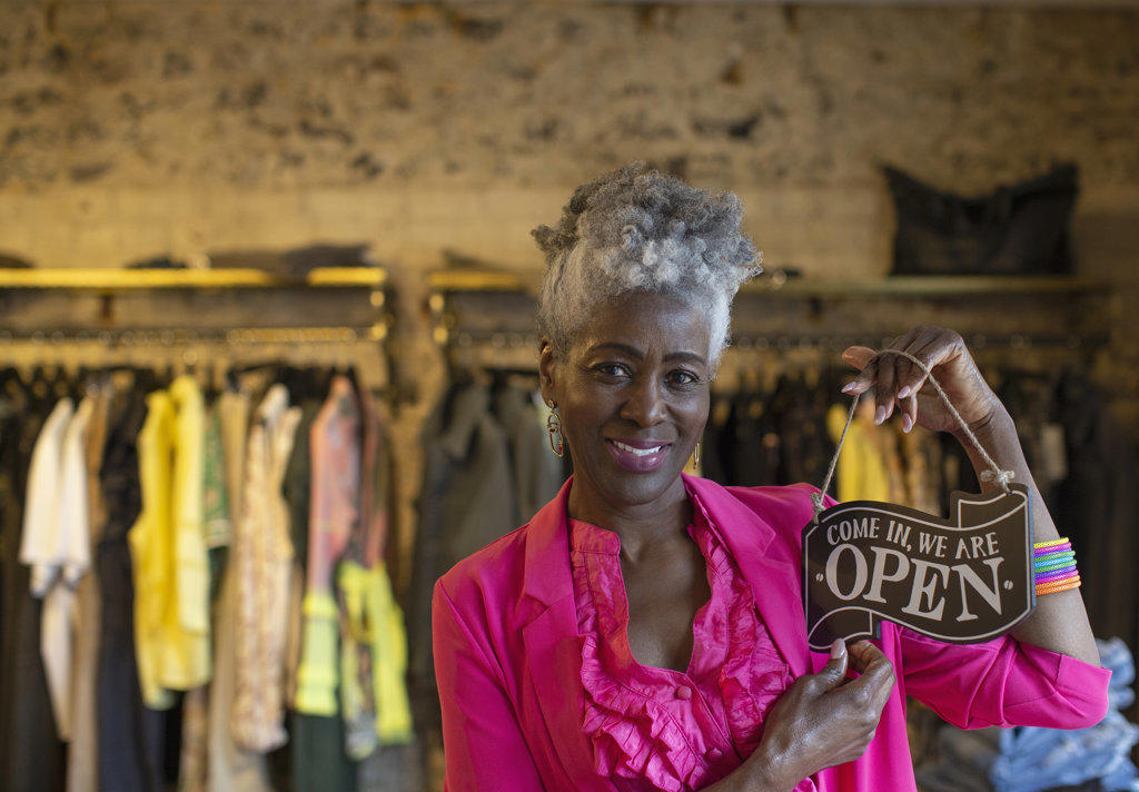 Portrait confident senior female shop owner holding open sign