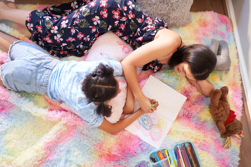 View from above mother and daughter drawing circles in notebook