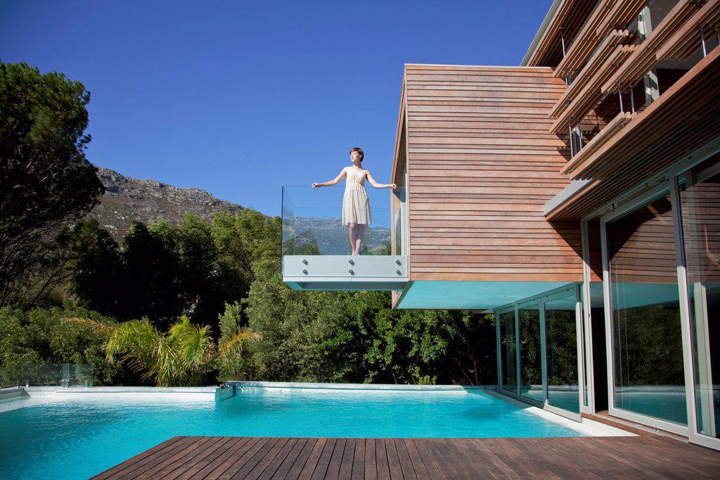Woman standing on balcony over swimming pool