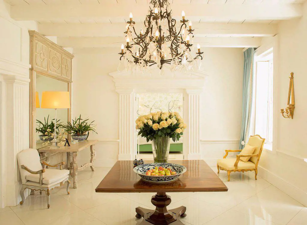 Chandelier over rose bouquet on table in luxury foyer