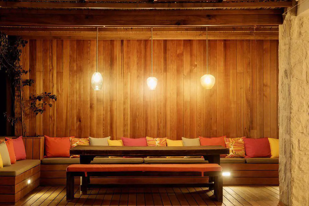 Pendant lights illuminated over patio bench with cushions
