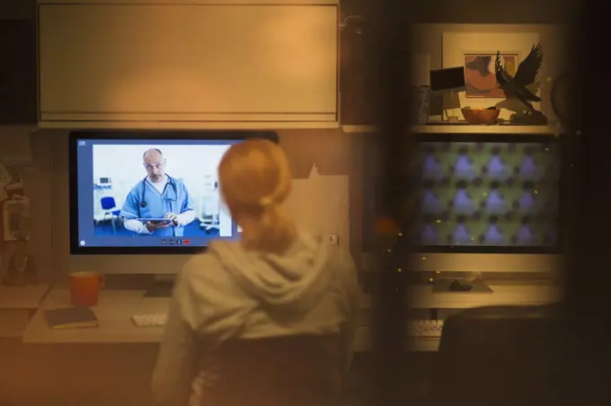 Woman video conferencing with doctor on computer screen