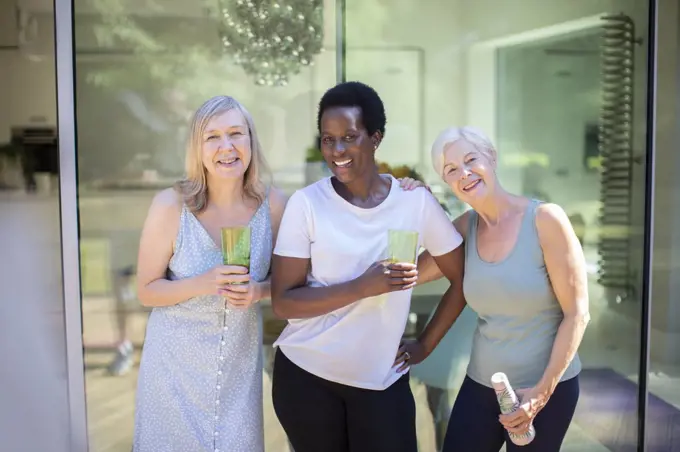 Portrait happy confident senior women drinking water on summer patio