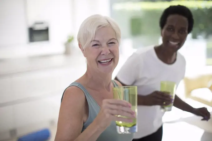 Portrait happy senior women friends drinking water at home