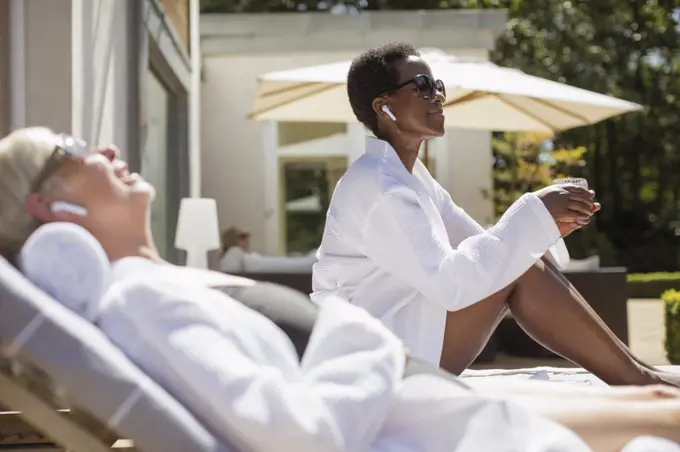 Carefree senior women in spa robes relaxing on sunny hotel patio