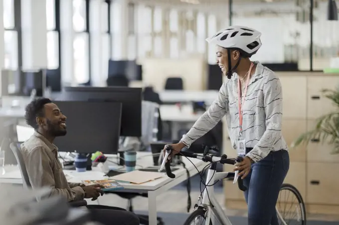 Businesswoman with bicycle talking to businessman in office