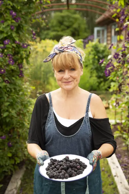 Portrait proud woman with fresh harvested blackberries in garden