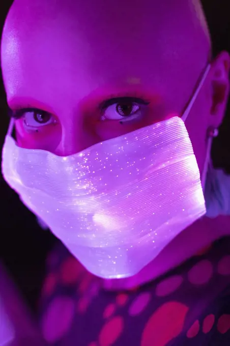 Close up portrait woman with shaved head in glowing face mask