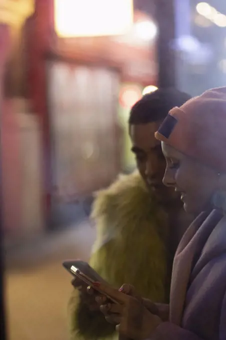 Stylish young couple using smart phones on urban sidewalk