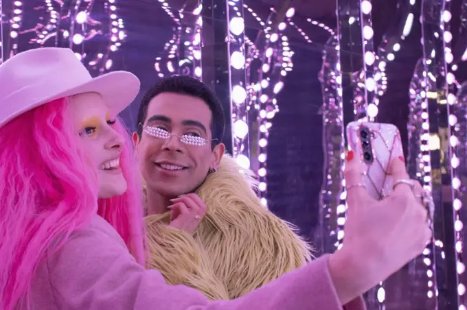 Eccentric fashionable couple taking selfie with camera phone