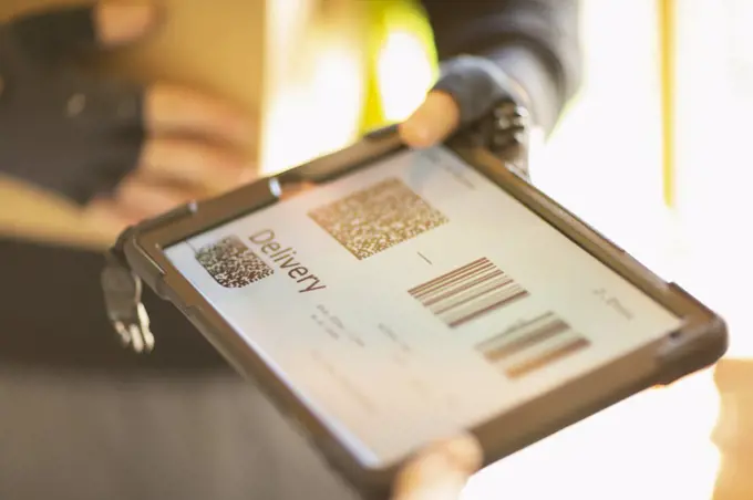 Close up courier holding digital tablet with delivery QR codes