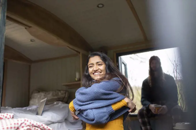 Happy young woman removing sweater in tiny cabin rental