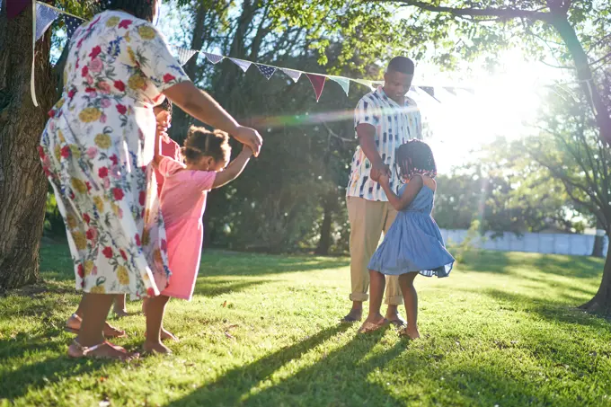 Family dancing in sunny summer backyard grass