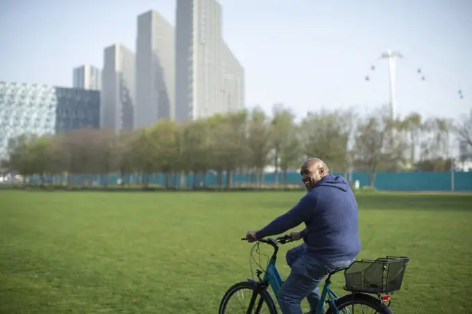 Happy man riding bicycle in urban park grass
