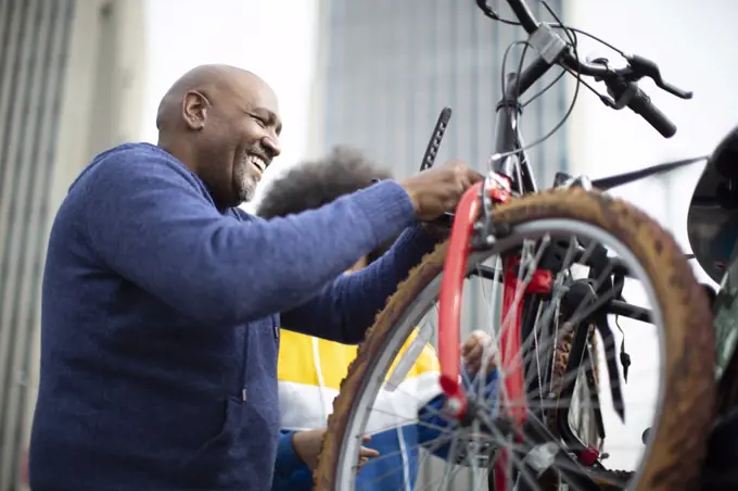 Happy man placing. bicycle on car bike rack in city