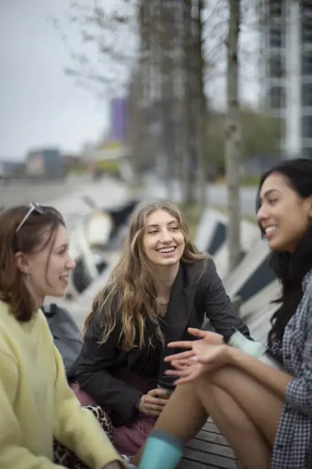 Happy young women friends talking in city
