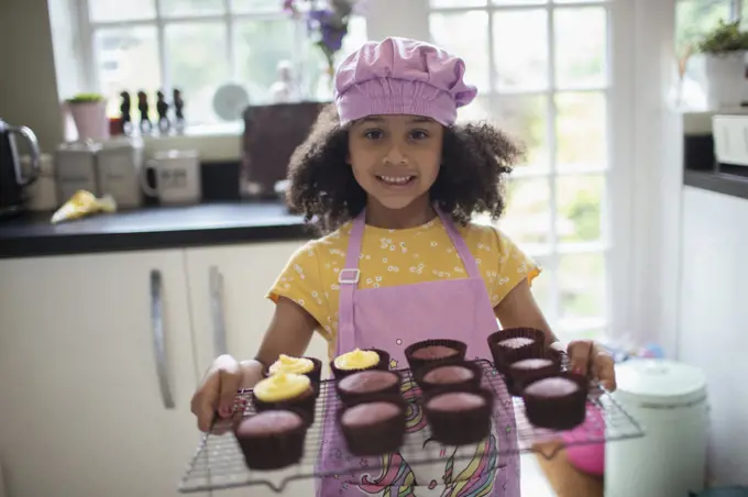 Portrait happy cute girl baking cupcakes on rack