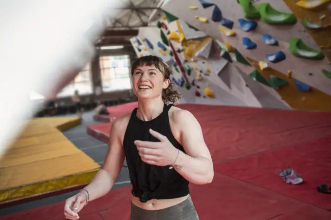 Happy young female rock climber in climbing gym