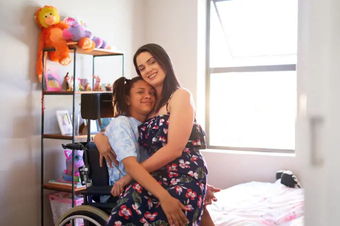 Portrait happy, affectionate mother hugging disabled daughter at home