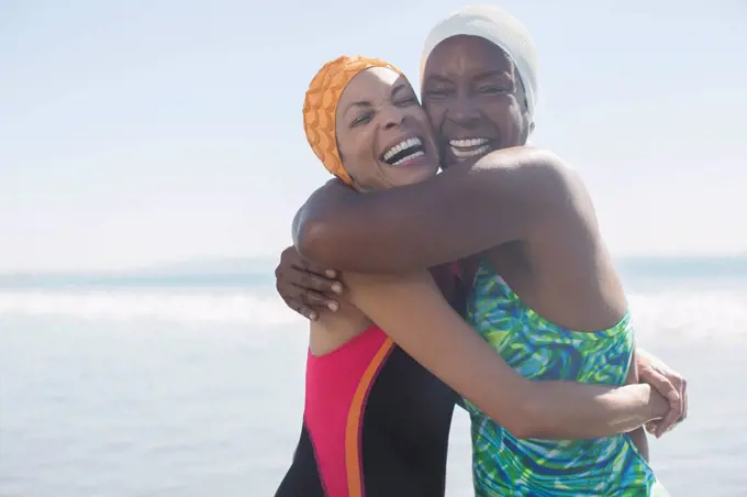Enthusiastic women hugging in bathing suits and caps