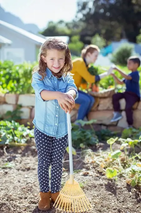 Girl holding rake in garden