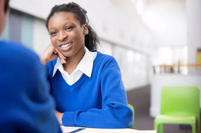 Smiling teenage student sitting at desk in school