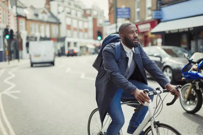 Businessman commuting, riding bicycle on urban street