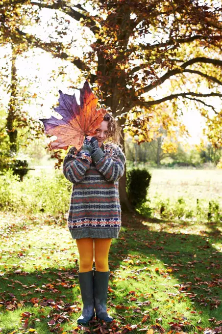 Girl playing with autumn leaf outdoors,belmonthouse, UK