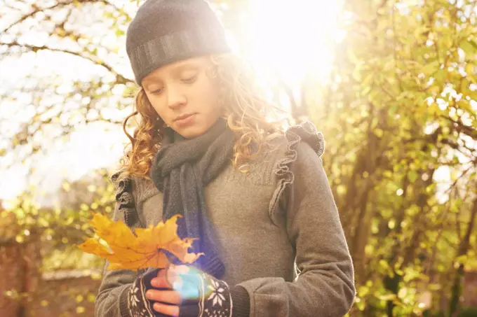 Girl carrying autumn leaf outdoors,belmonthouse, UK