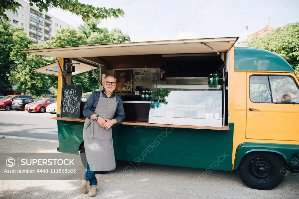Portrait of mature man standing against food truck