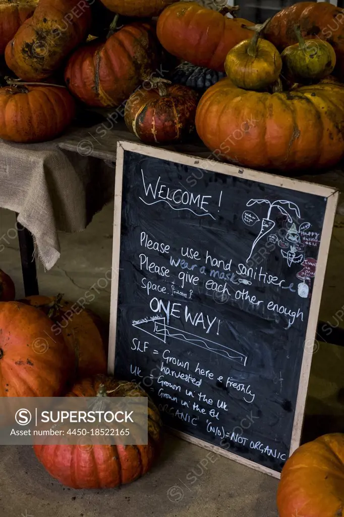 Pumpkins and blackboard with welcome note in a farm shop.