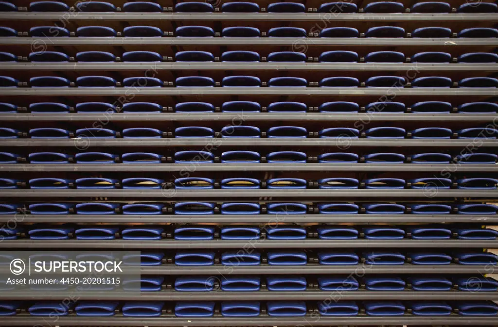A row of folded seats on shelves in an indoor sports venue.