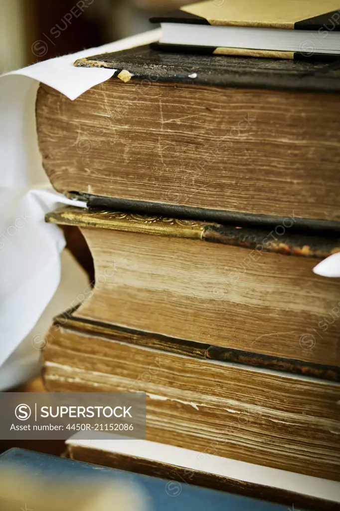 A stack of books, with yellowed worn page edges and worn bindings.