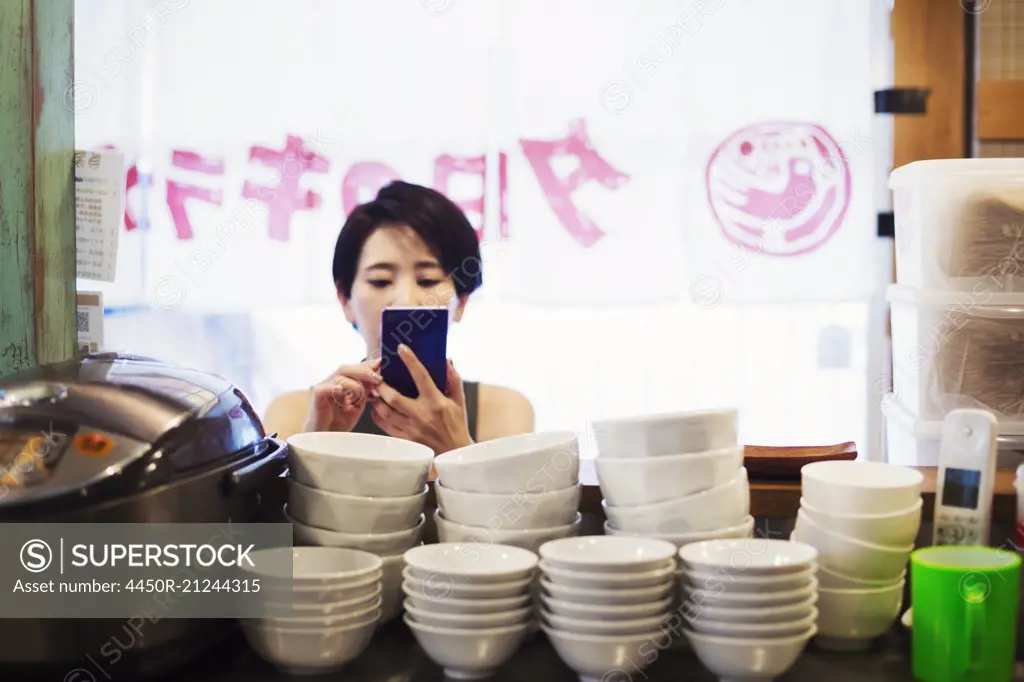 A woman using a smart phone at a noodle shop.