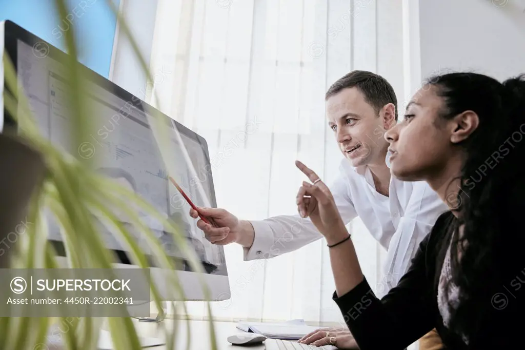 Man and woman discussing data on a large computer screen
