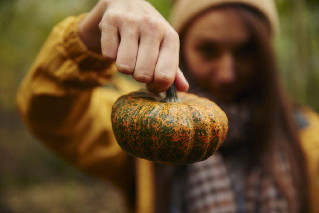 Woman holding up pumpkin to camera