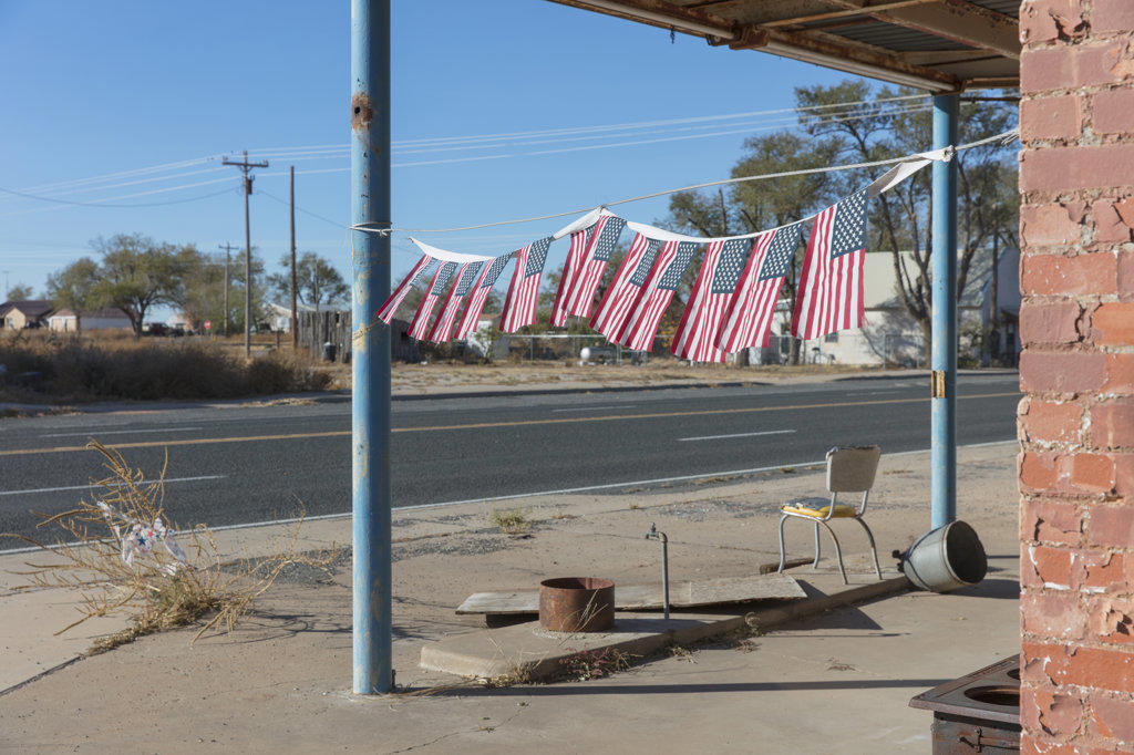 American flags in front of abandoned gas station.