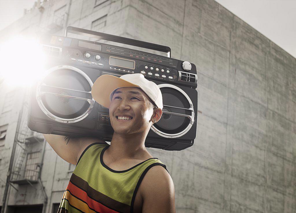 A young person with a boombox on the street of a city.