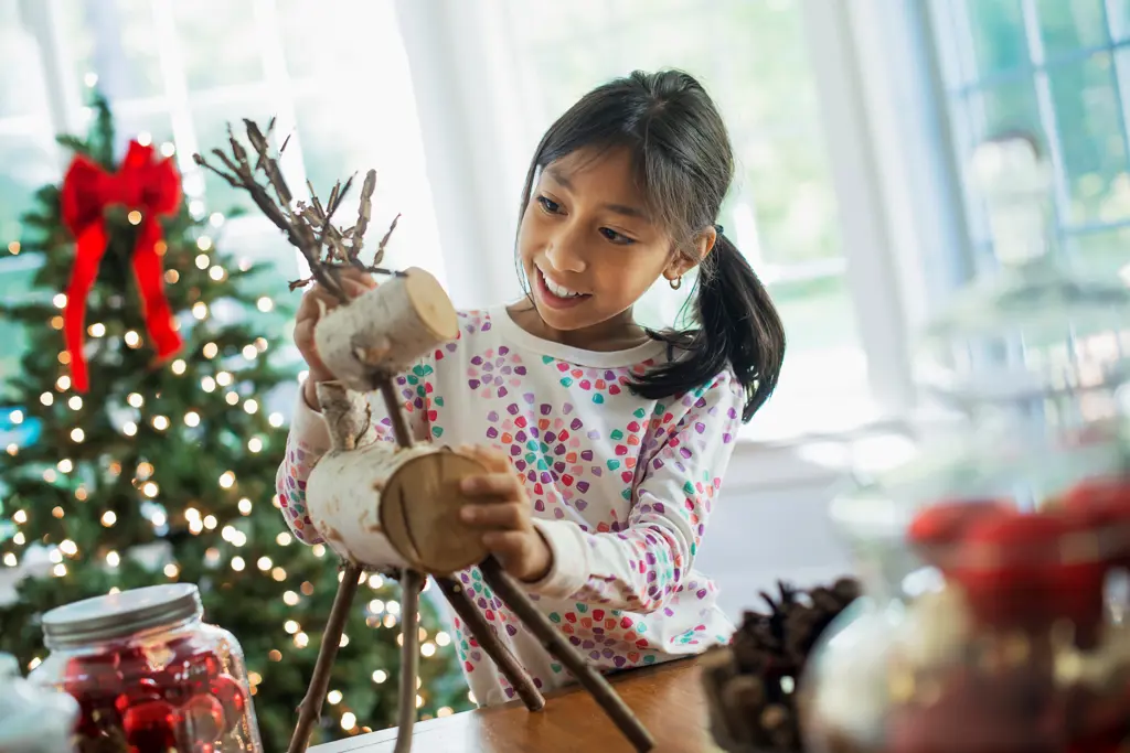 A young girl assembling a twig figure of a reindeer, making Christmas decorations. Woodstock, New York, USA. 9/9/2012